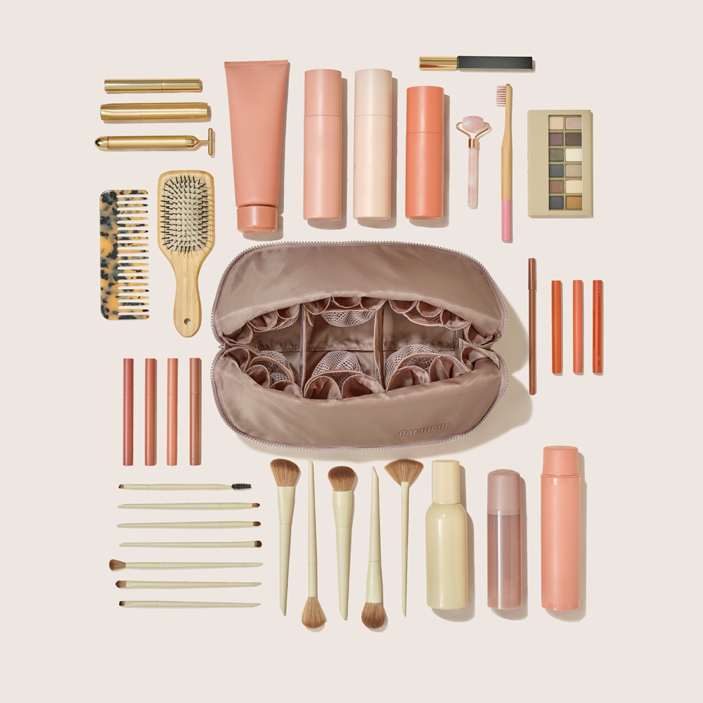 Overhead view of the Large Bronze Traveller surrounded by by makeup brushes, skincare bottles, tubes, and palettes. Compact travel case for beauty essentials.