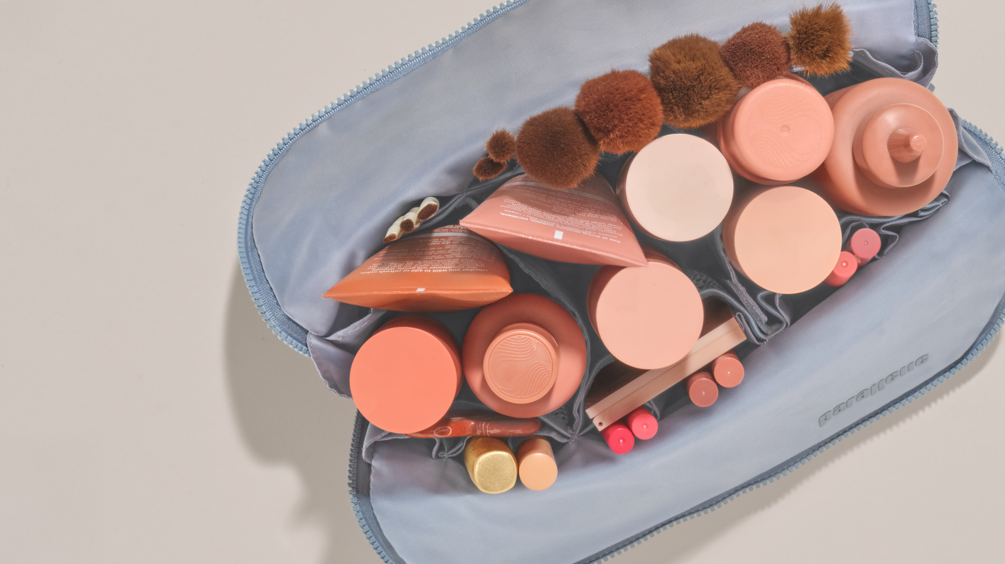 Overhead view of the Large Slate Traveller, fully packed with makeup brushes, tubes, and upright bottles inside flexible compartments.