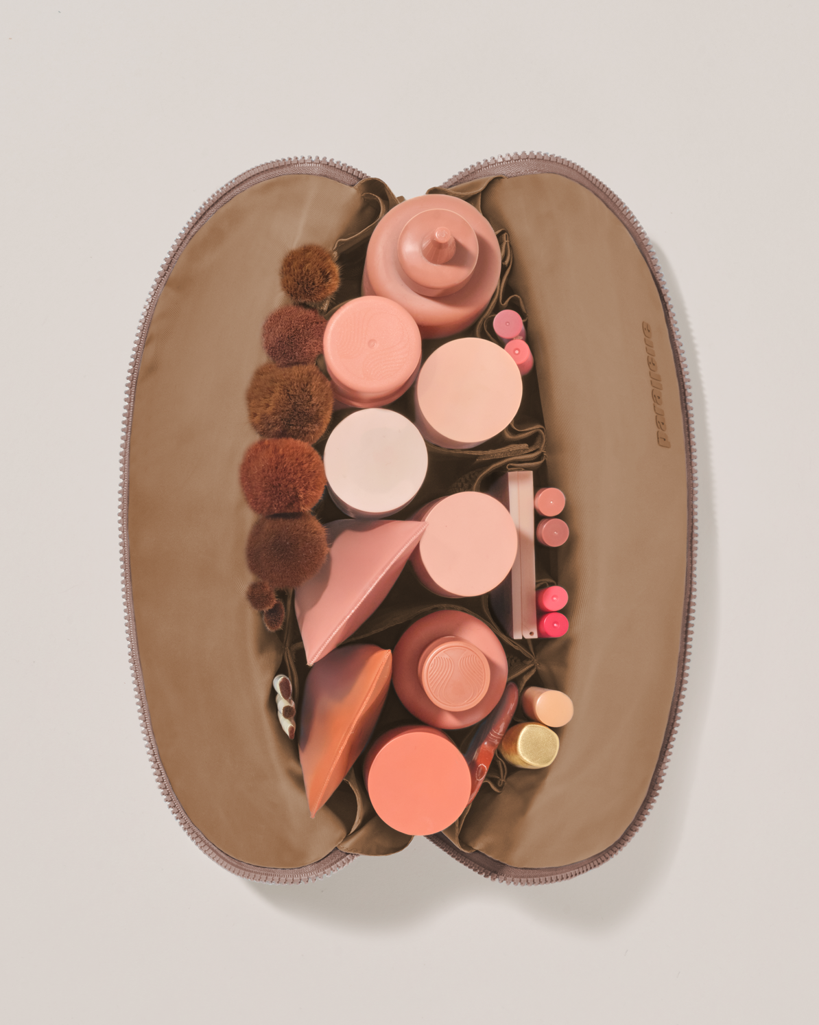Overhead view of the Large Bronze Traveller makeup bag fully packed with upright beauty products and organized compartments