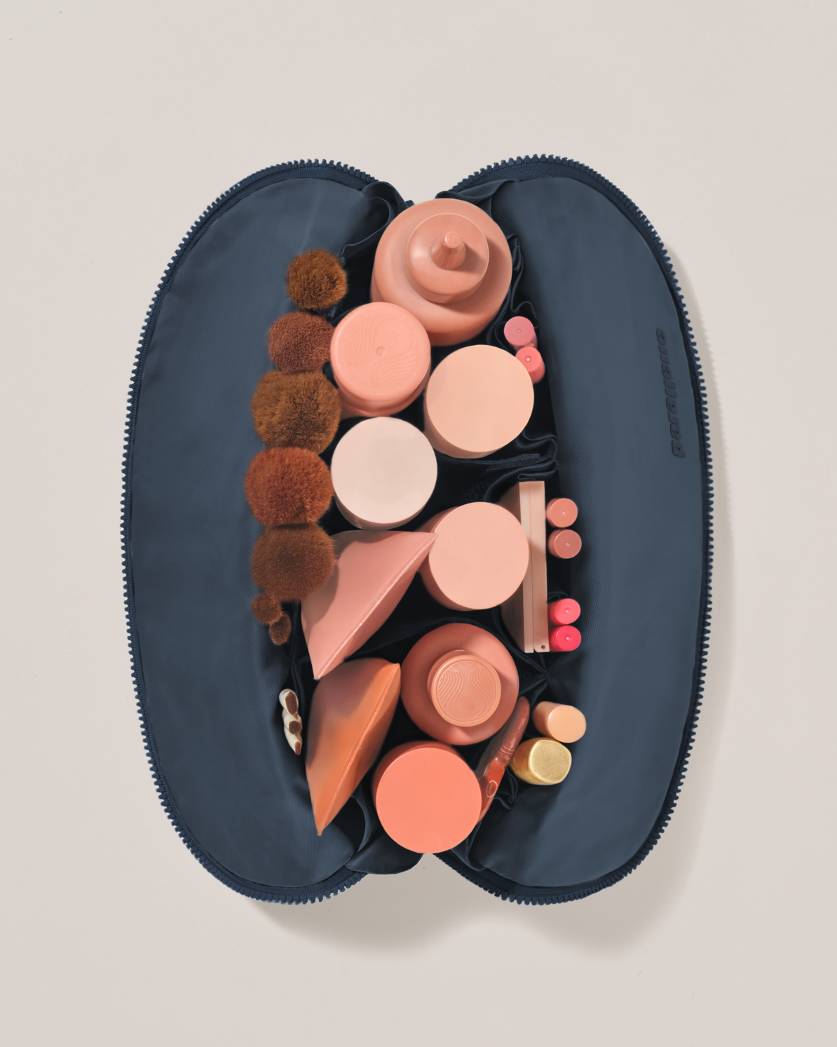 Overhead view of the Large Indigo (navy) Traveller makeup bag fully packed with upright beauty products and organized compartments
