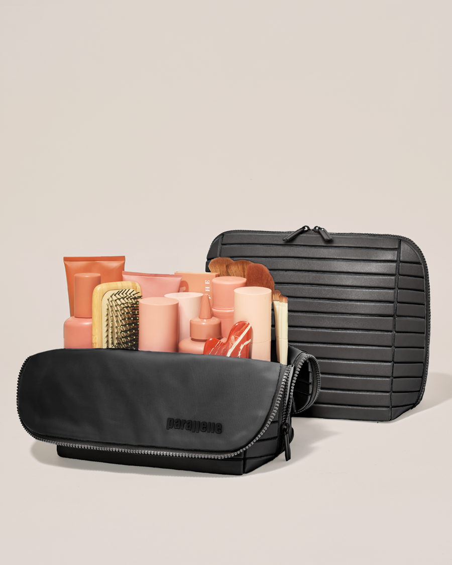 Open and closed Parallelle Large Onyx (black) Traveller makeup bag showing skincare, brushes, and curated travel essentials