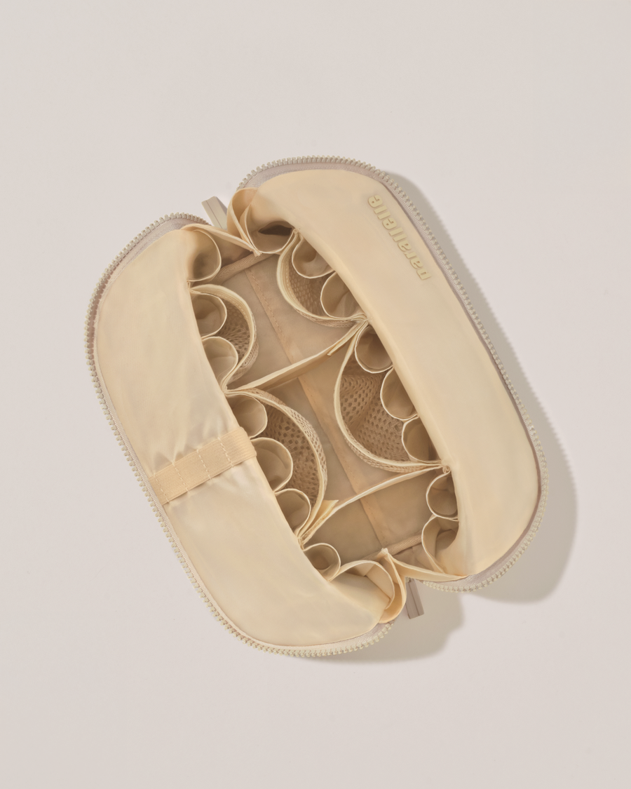 Interior view of Parallelle Medium Bisque (white) Traveller makeup bag showing empty pockets, pouches, and elastic holders