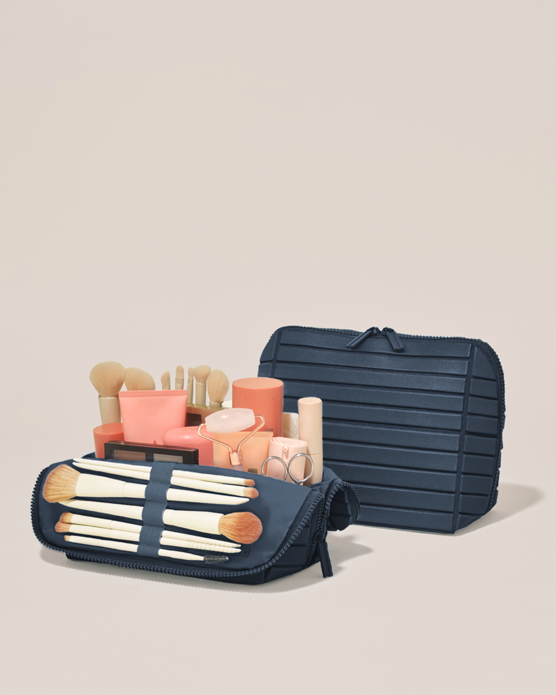 Open and closed Parallelle Medium Indigo (navy) Traveller makeup bag showing skincare, brushes, and curated travel essentials