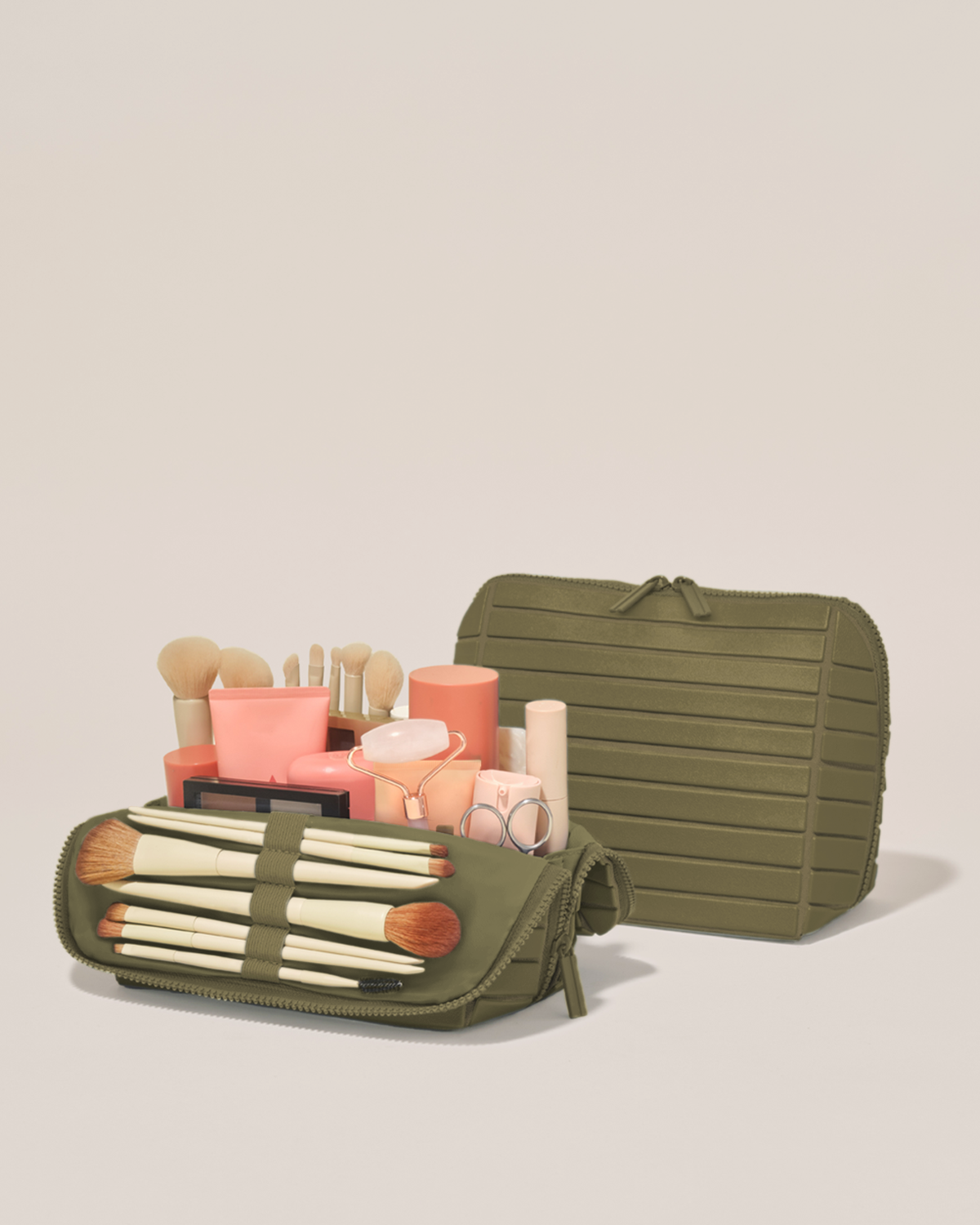 Open and closed Parallelle Medium Olive (green) Traveller makeup bag showing skincare, brushes, and curated travel essentials