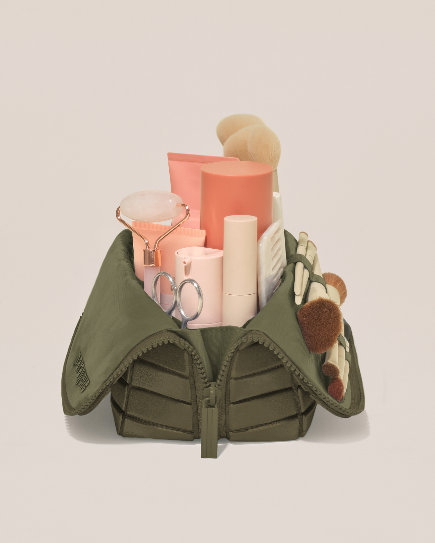 Side profile of the Medium Olive (green) Traveller makeup bag filled with beauty essentials standing upright, showing flexible compartment design