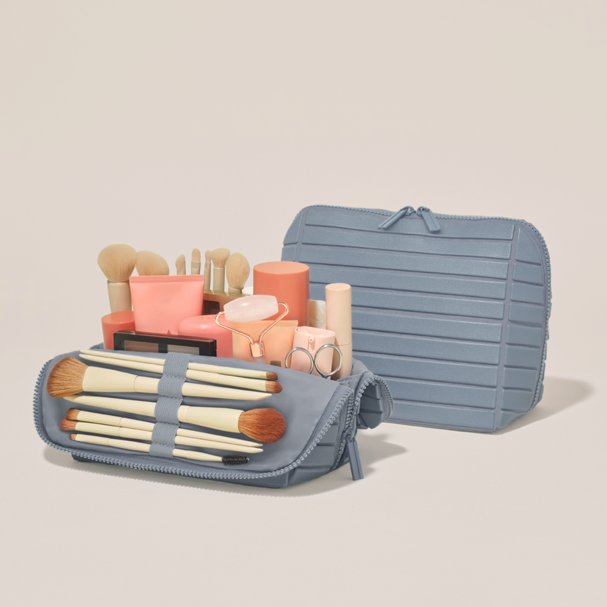 Open and closed Parallelle Medium Slate (blue) Traveller makeup bag showing skincare, brushes, and curated travel essentials