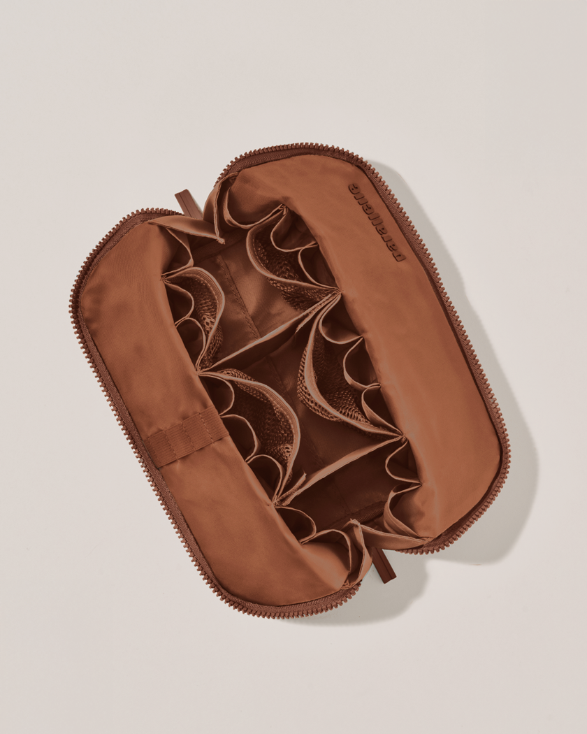 Interior view of Parallelle Medium Vicuna (brown) Traveller makeup bag showing empty pockets, pouches, and elastic holders