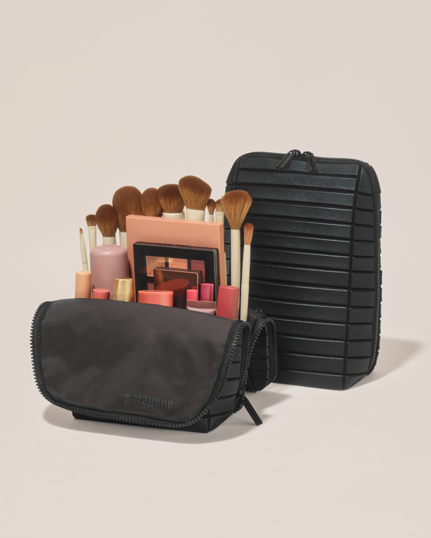 Open and closed Parallelle Onyx (black) Brush Traveller makeup bag showing skincare, brushes, and curated travel essentials