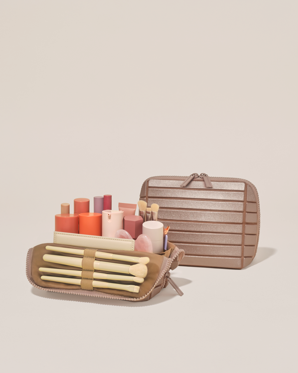 Open and closed Parallelle Small Bronze Traveller makeup bag showing skincare, brushes, and curated travel essentials