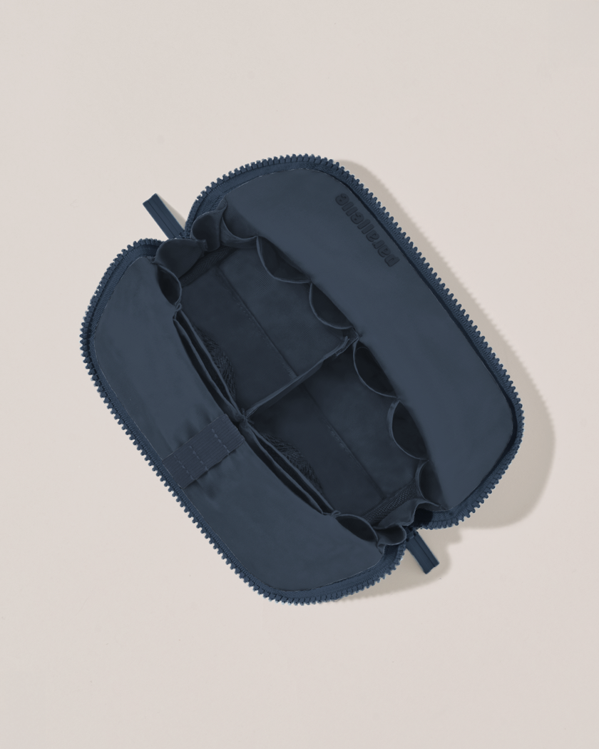 Interior view of Parallelle Small Indigo (navy) Traveller makeup bag showing empty pockets, pouches, and elastic holders