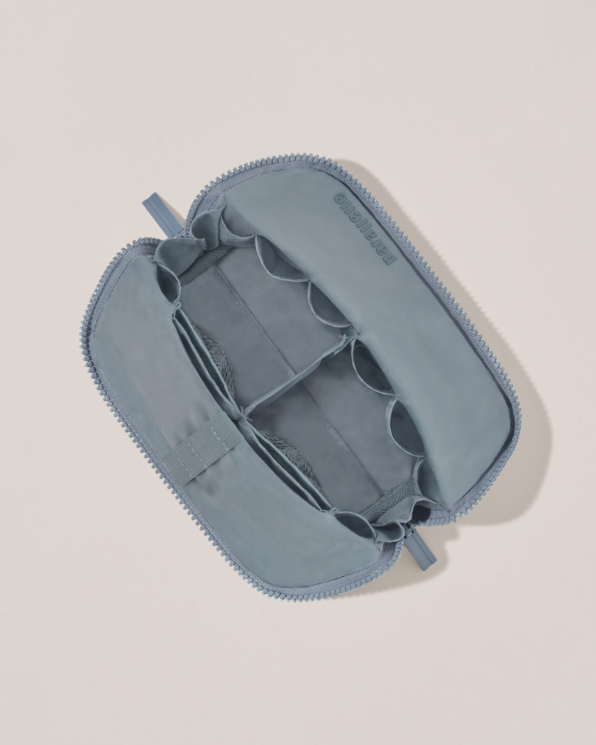 Interior view of Parallelle Small Slate (blue) Traveller makeup bag showing empty pockets, pouches, and elastic holders