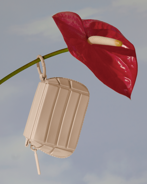 The Bisque Key Charm shown hanging on a flower