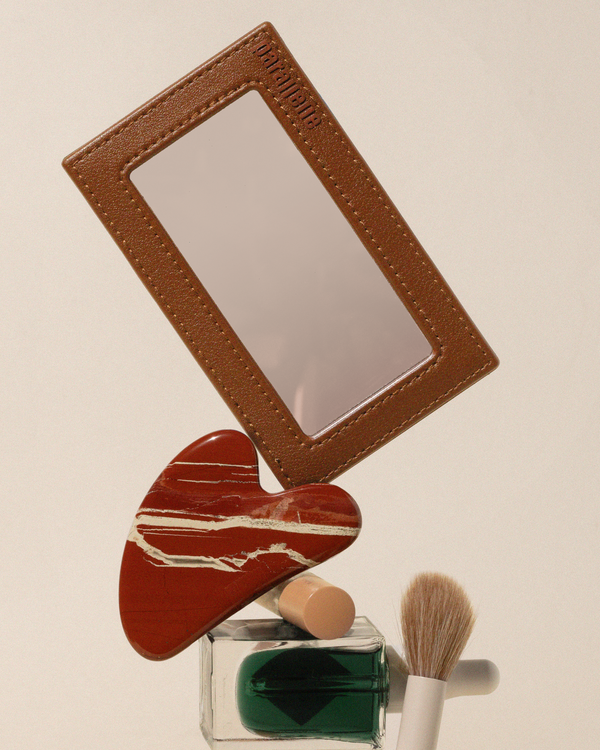 The Mirror shown on top of various beauty items