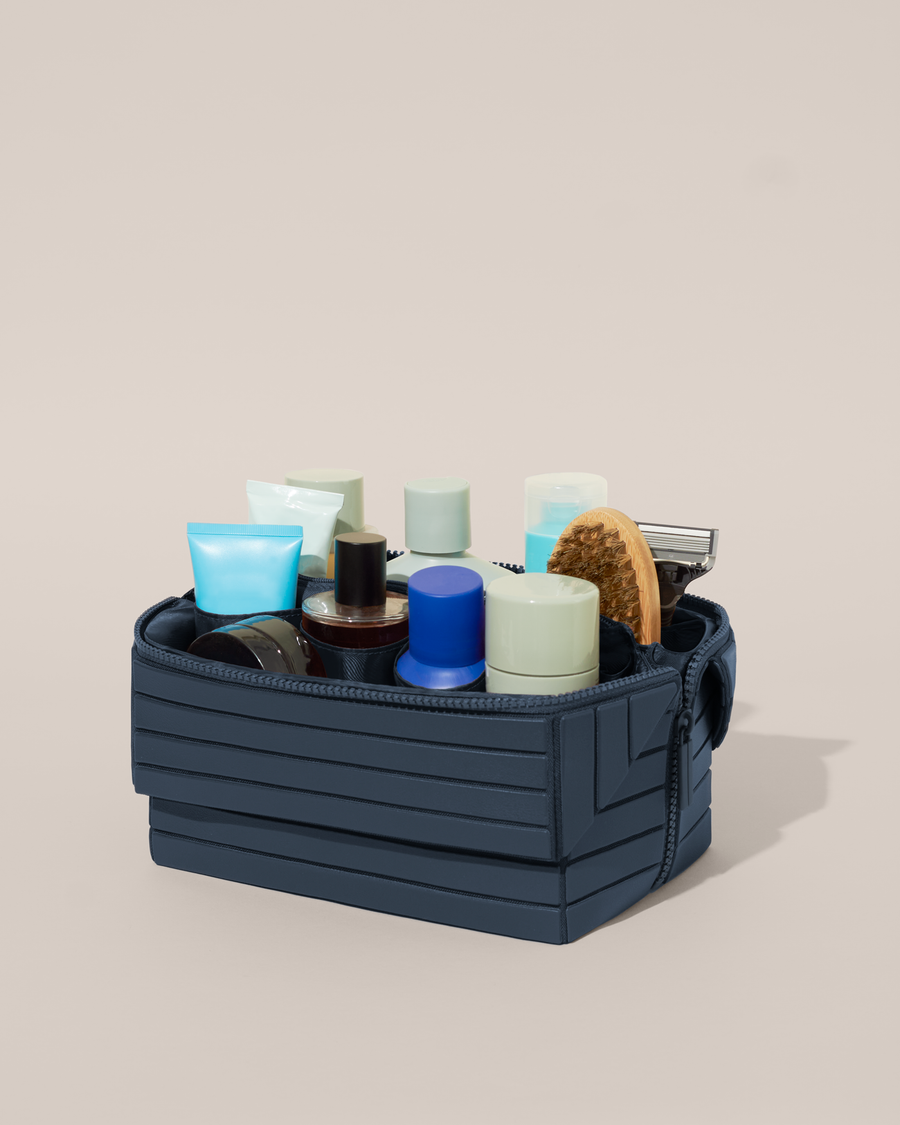 Open Parallelle Indigo (blue) Kit, shown open and packed with grooming essentials like razors, cologne, and skincare. A structured, travel-ready toiletry organizer