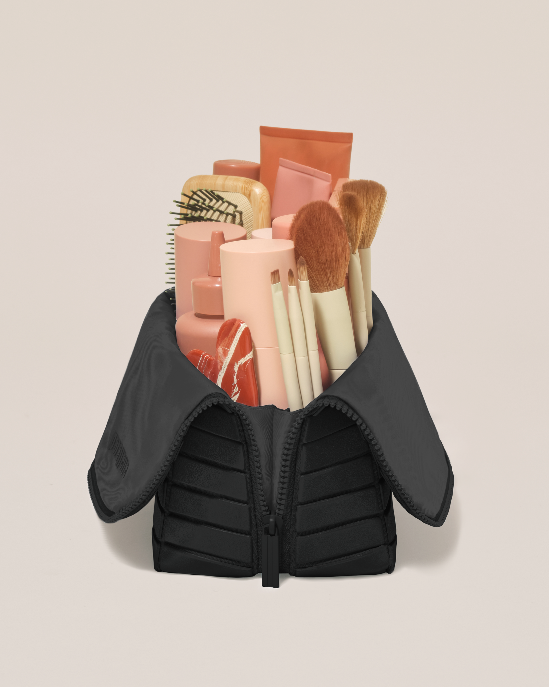 Side profile of the Large Onyx (black) Traveller makeup bag filled with beauty essentials standing upright, showing flexible compartment design