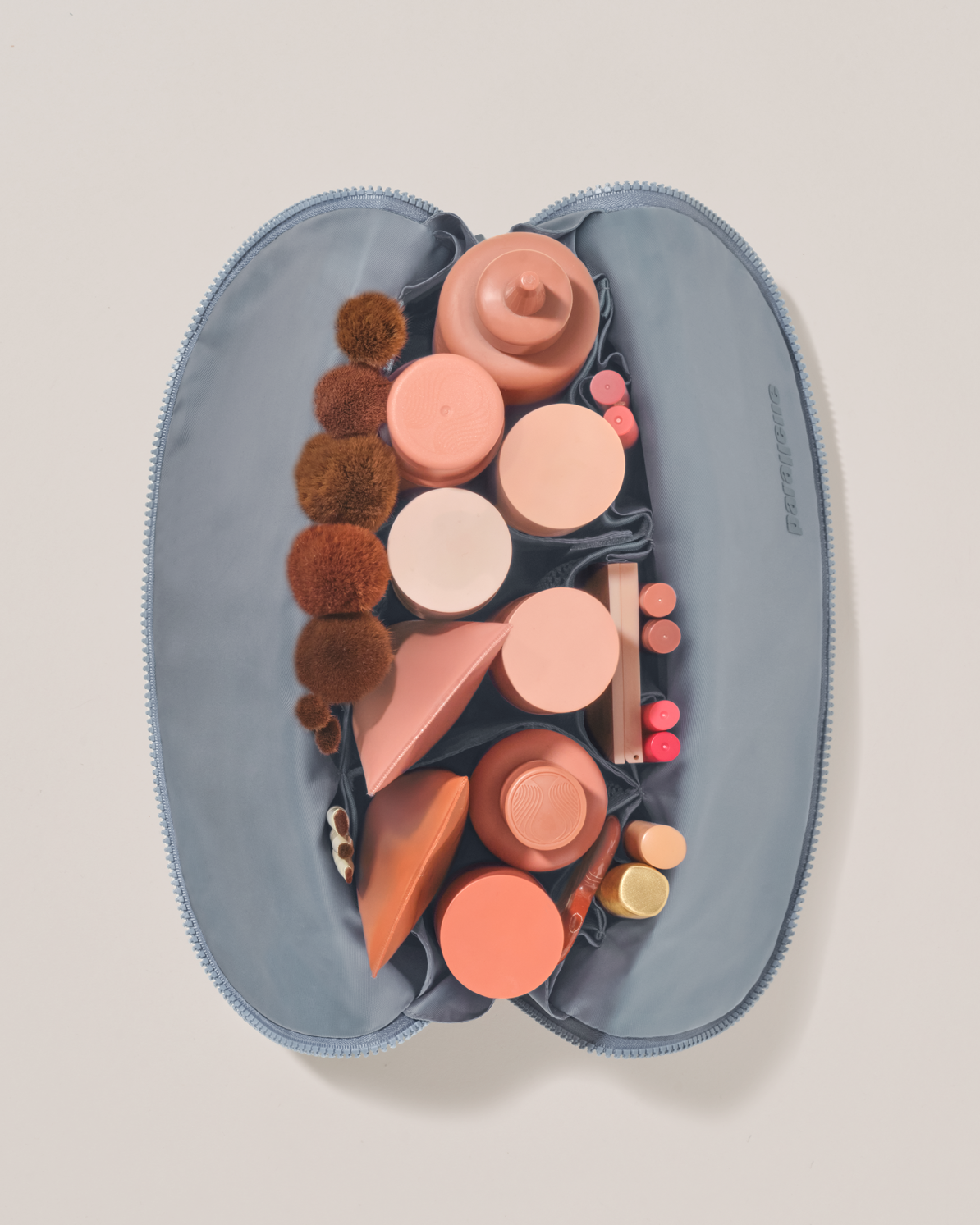 Overhead view of the Large Slate (blue) Traveller makeup bag fully packed with upright beauty products and organized compartments