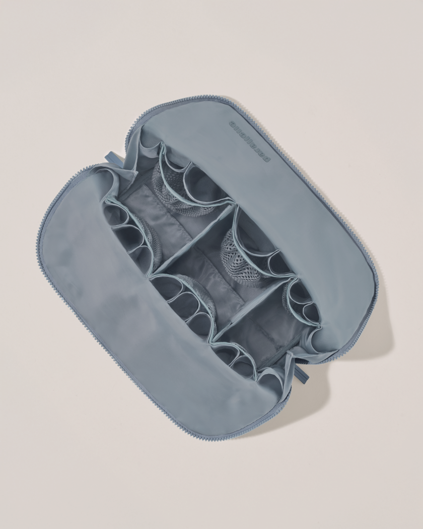 Interior view of Parallelle Large Slate (blue) Traveller makeup bag showing empty pockets, pouches, and elastic holders