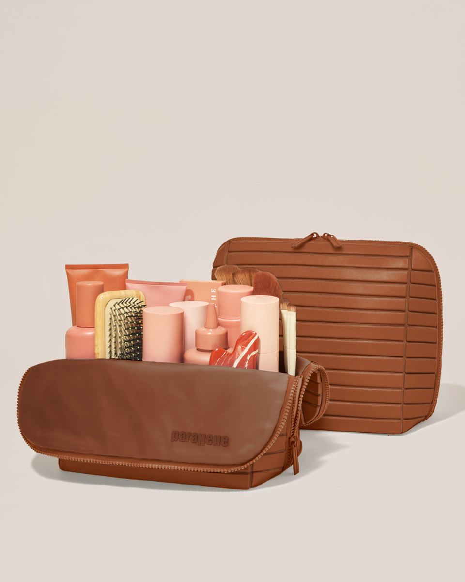 Open and closed Parallelle Large Vicuna (brown) Traveller makeup bag showing skincare, brushes, and curated travel essentials