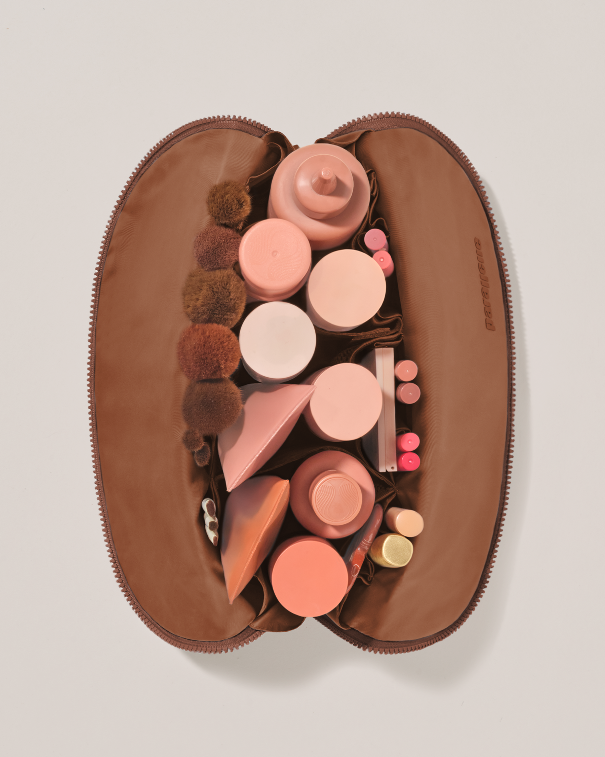 Overhead view of the Large Vicuna (brown) Traveller makeup bag fully packed with upright beauty products and organized compartments