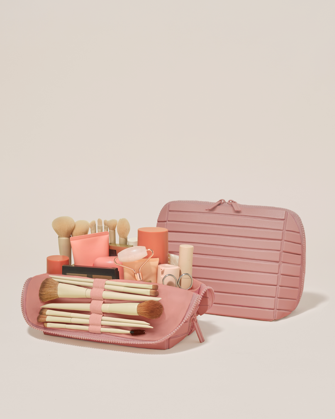 Open and closed Parallelle Medium Blush (pink) Traveller makeup bag showing skincare, brushes, and curated travel essentials