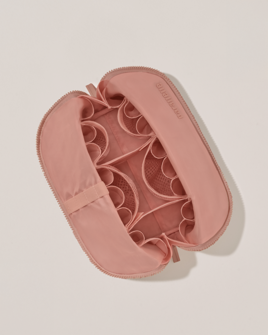 Interior view of Parallelle Medium Blush (pink) Traveller makeup bag showing empty pockets, pouches, and elastic holders