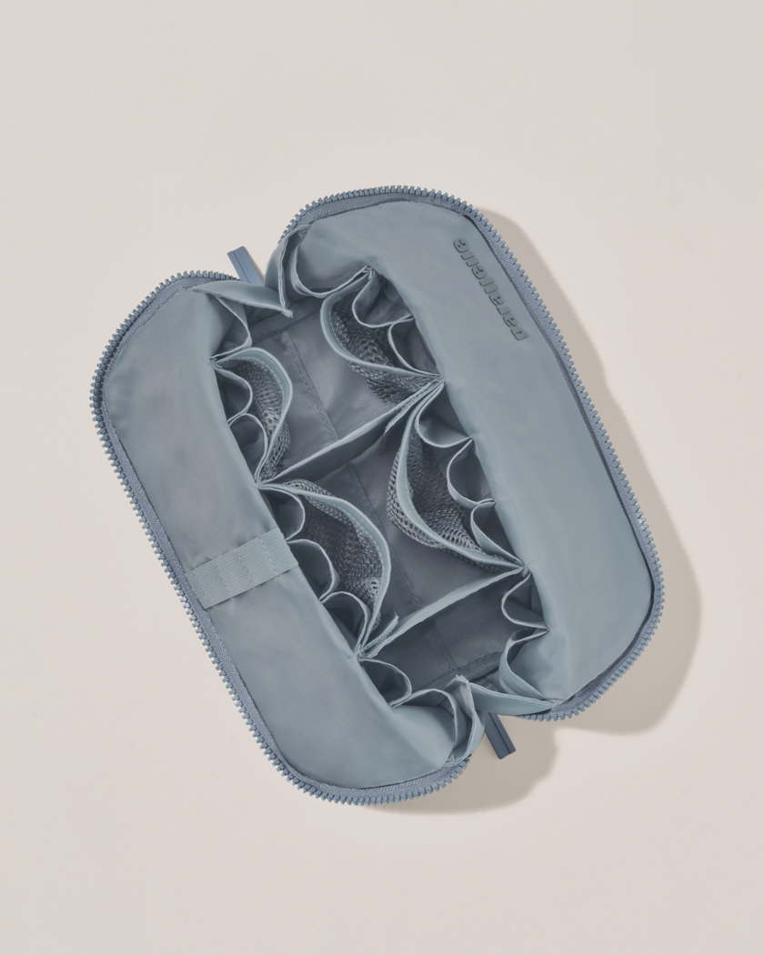 Interior view of Parallelle Medium Slate (blue) Traveller makeup bag showing empty pockets, pouches, and elastic holders
