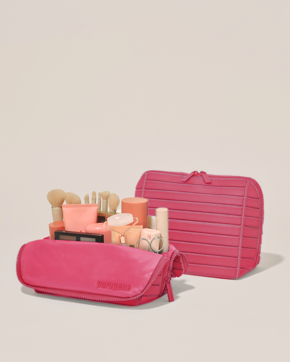 Open and closed Parallelle Medium Tart (hot pink) Traveller makeup bag showing skincare, brushes, and curated travel essentials