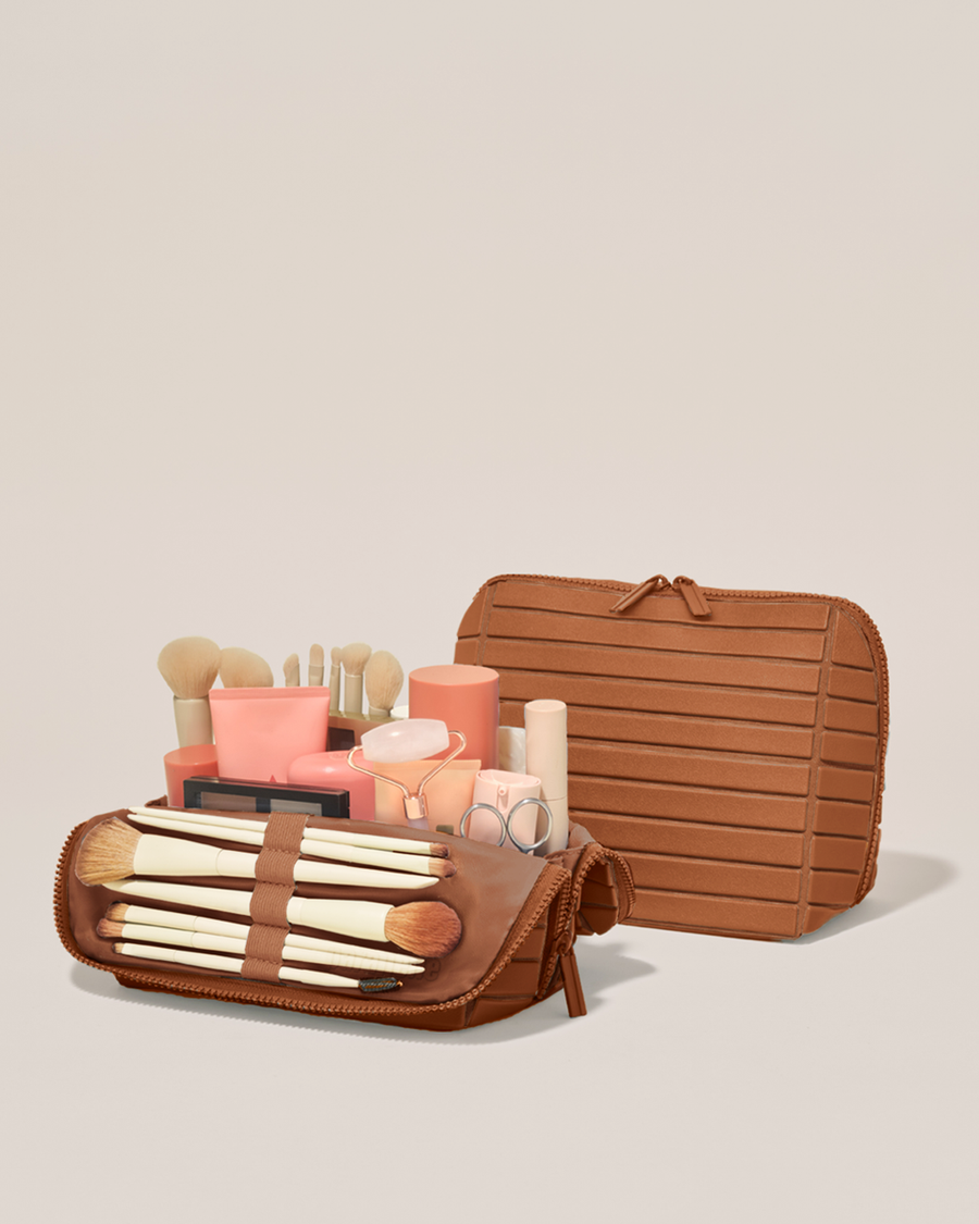 Open and closed Parallelle Medium Vicuna (brown) Traveller makeup bag showing skincare, brushes, and curated travel essentials
