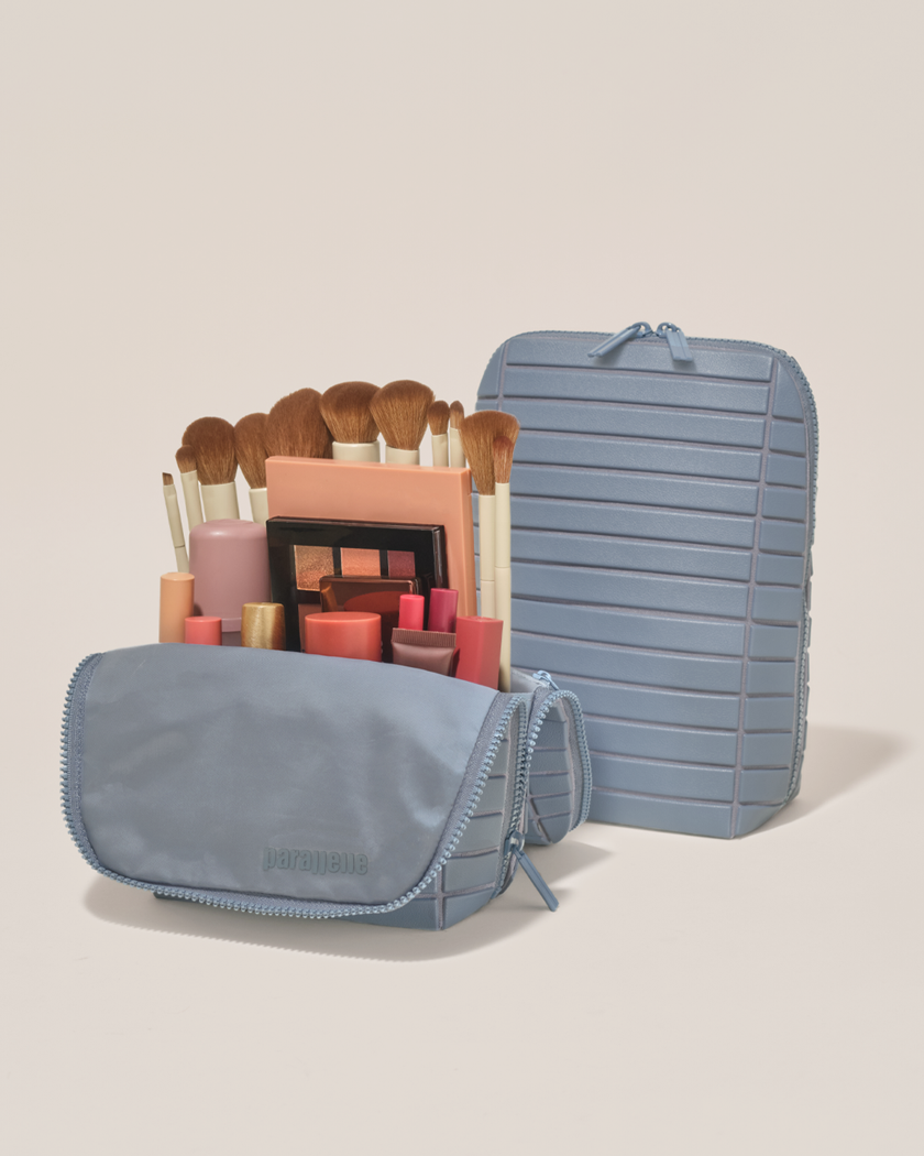 Open and closed Parallelle Slate (blue) Brush Traveller makeup bag showing skincare, brushes, and curated travel essentials