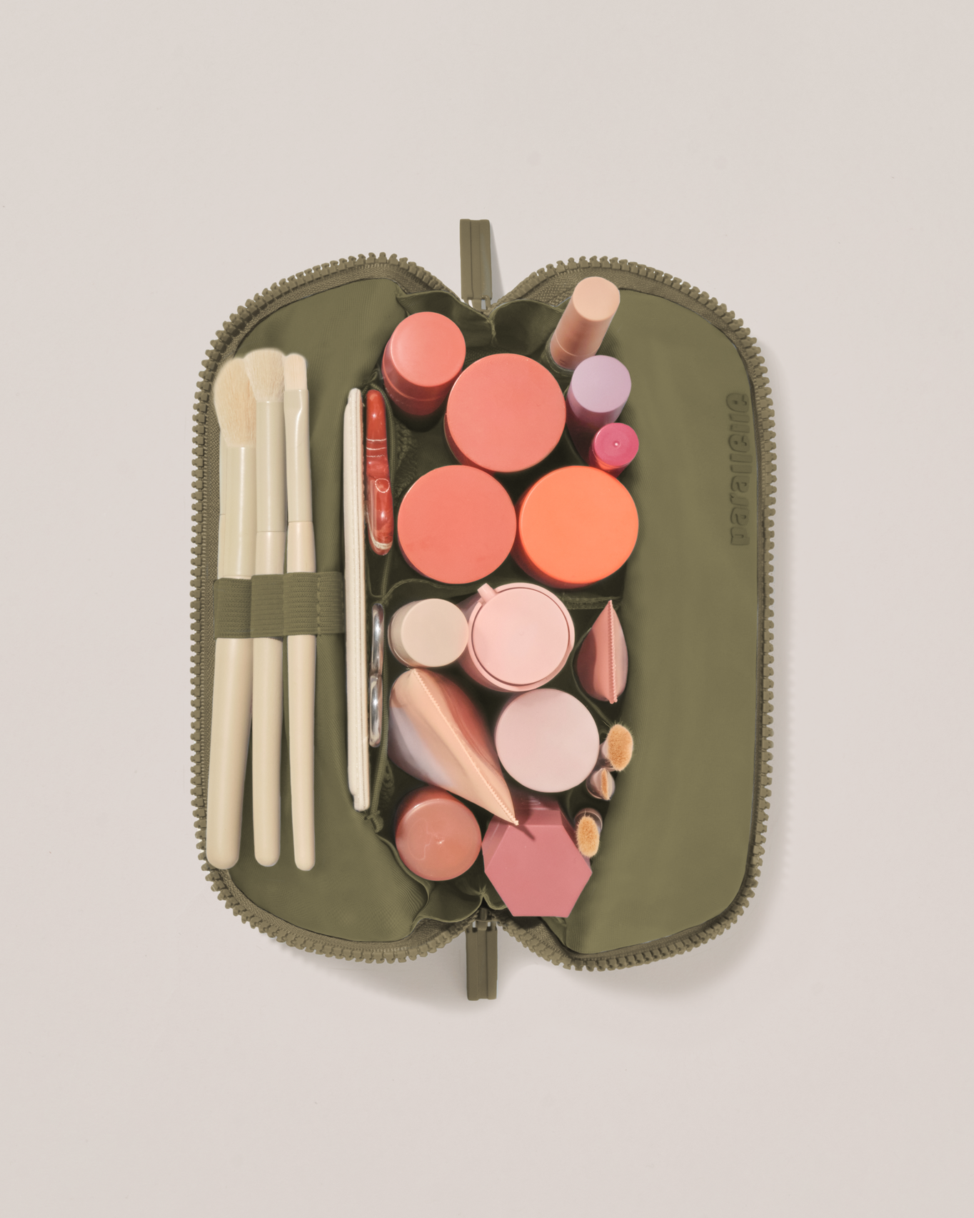 Overhead view of the Small Olive (green) Traveller makeup bag fully packed with upright beauty products and organized compartments