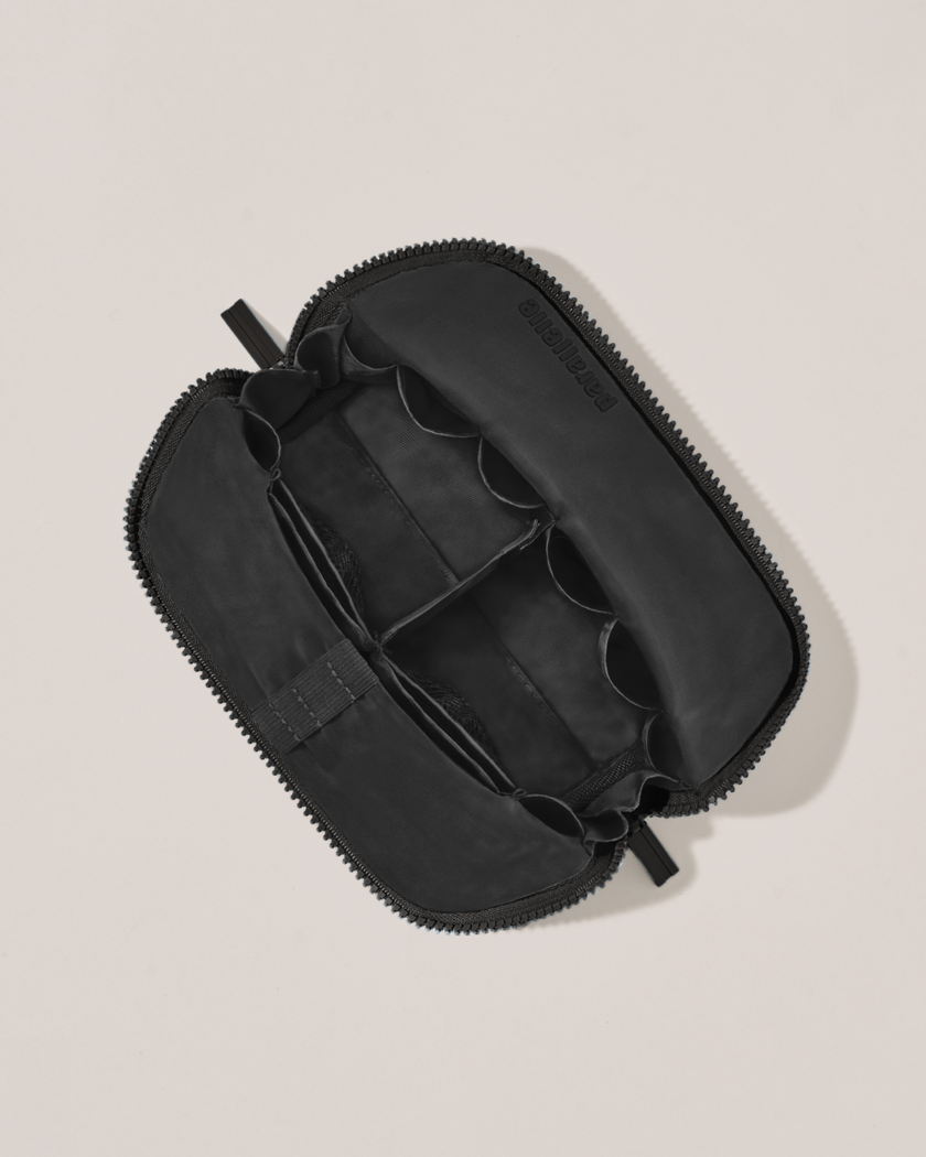 Interior view of Parallelle Small Onyx (black) Traveller makeup bag showing empty pockets, pouches, and elastic holders