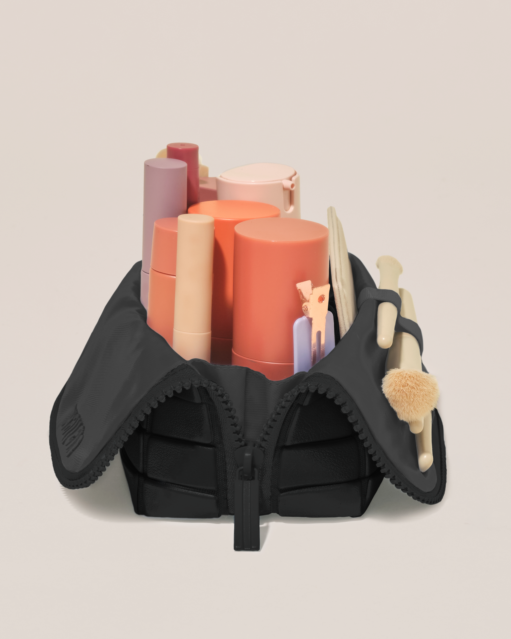 Side profile of the Small Onyx (black) Traveller makeup bag filled with beauty essentials standing upright, showing flexible compartment design