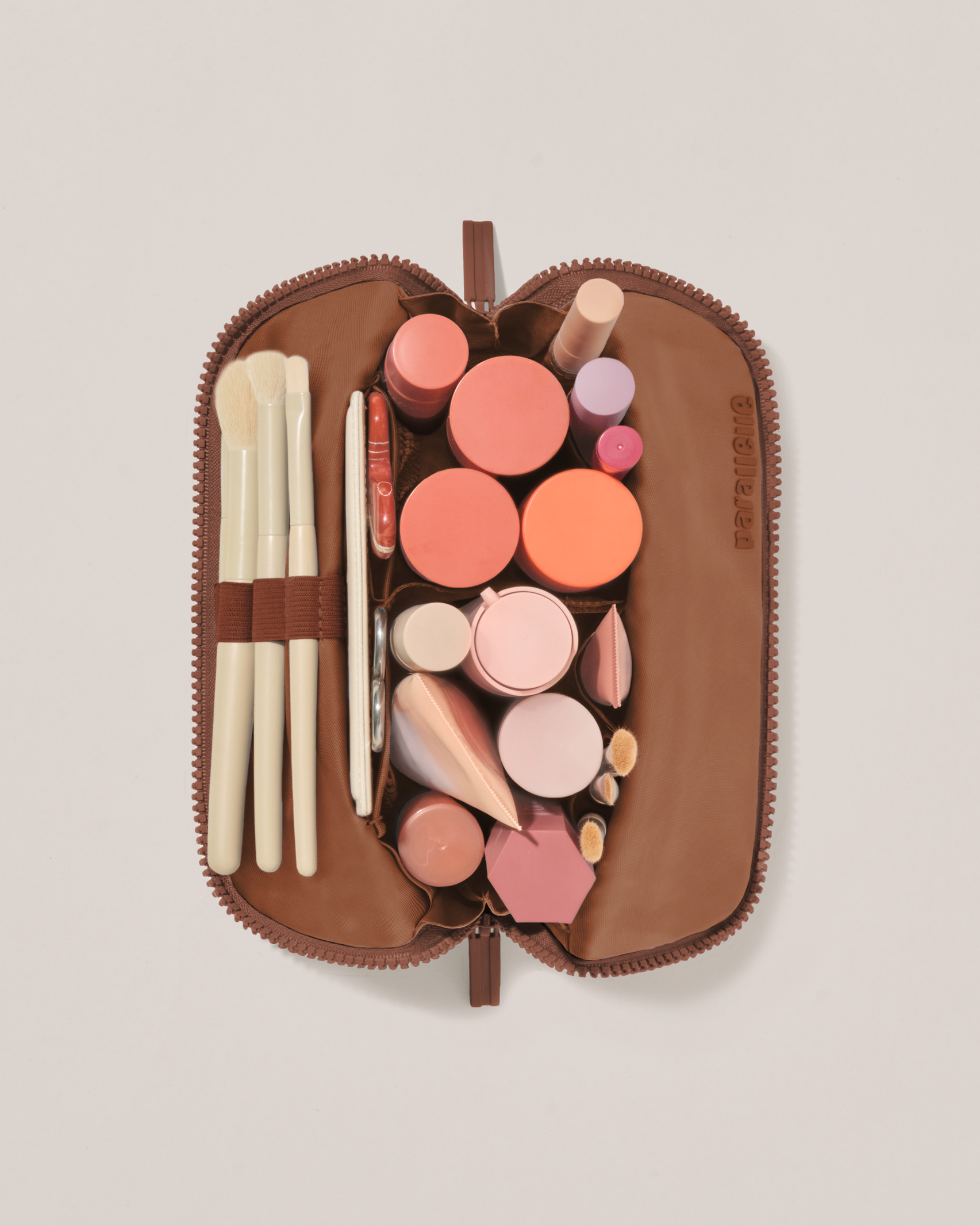 Overhead view of the Small Vicuna (brown) Traveller makeup bag fully packed with upright beauty products and organized compartments