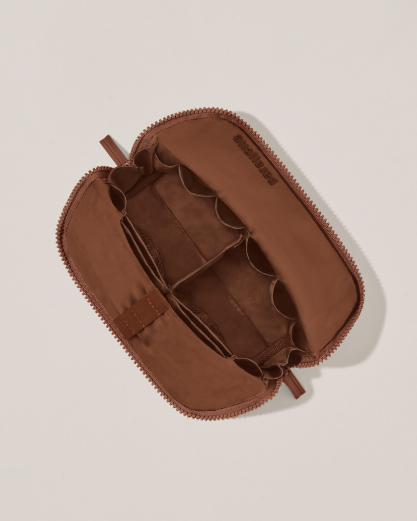 Interior view of Parallelle Small Vicuna (brown) Traveller makeup bag showing empty pockets, pouches, and elastic holders
