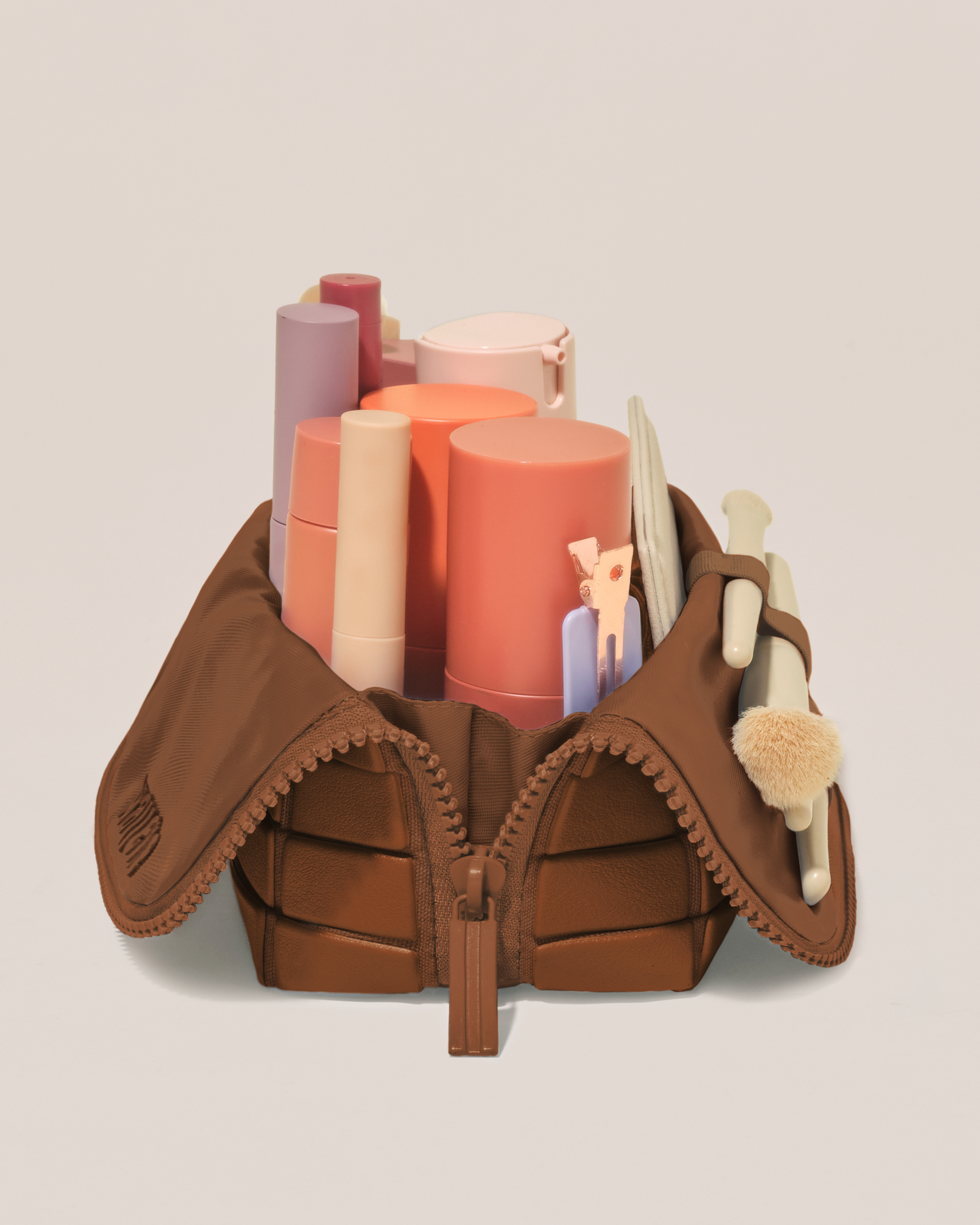 Side profile of the Small Vicuna (brown) Traveller makeup bag filled with beauty essentials standing upright, showing flexible compartment design